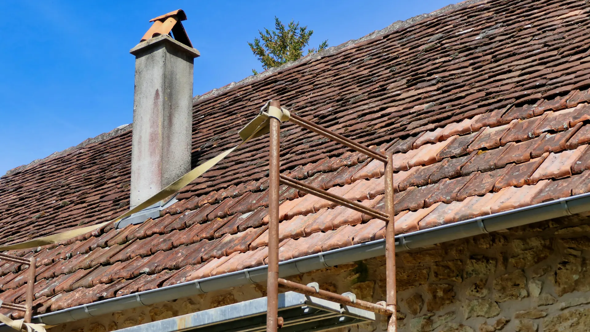 Clay tiled roof with a brick chimney and scaffolding in place for roof repairs