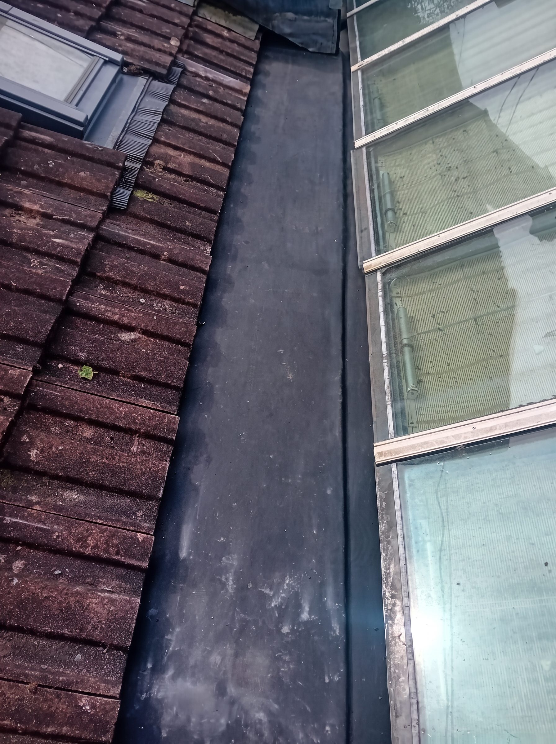 Lead valley gutter formed between a tiled roof and a glazed roof section